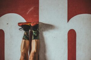 A person in colorful socks and sneakers exercising against a bold red wall.